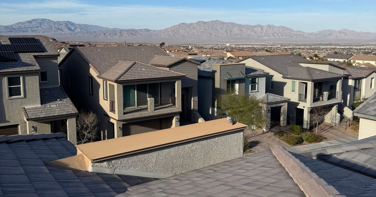 Two-story stucco homes with tile roofs in a Las Vegas valley subdivision, with mountains behind